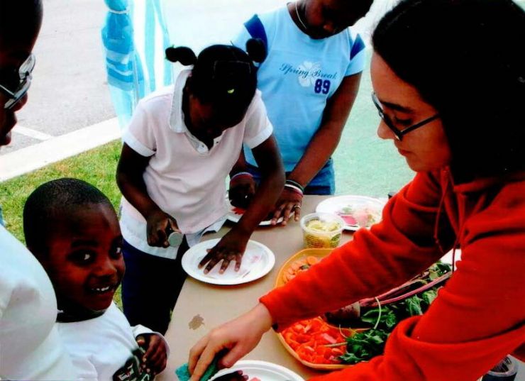 Dr. La Merrill showing local children how to paint with vegetables  to promote healthy eating.